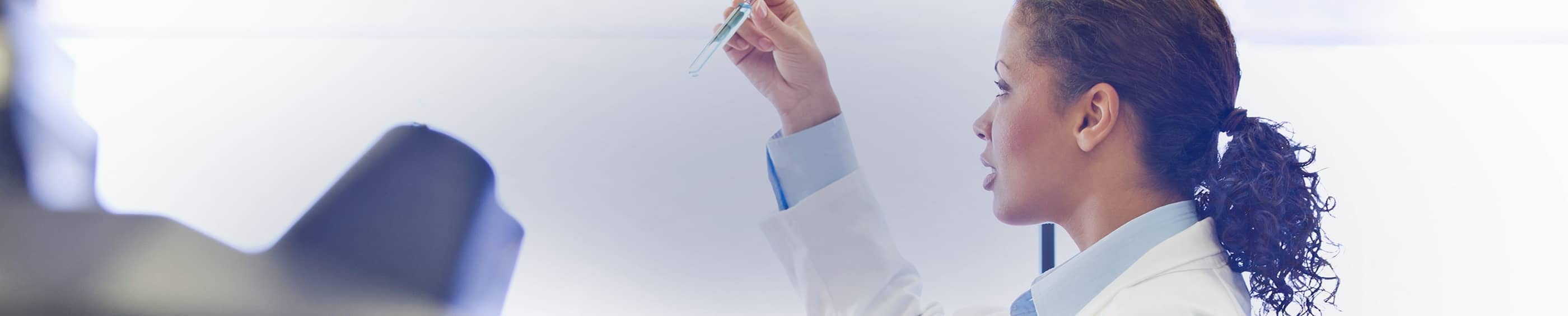 En læge i en kittel, der inspicerer et reagensglas