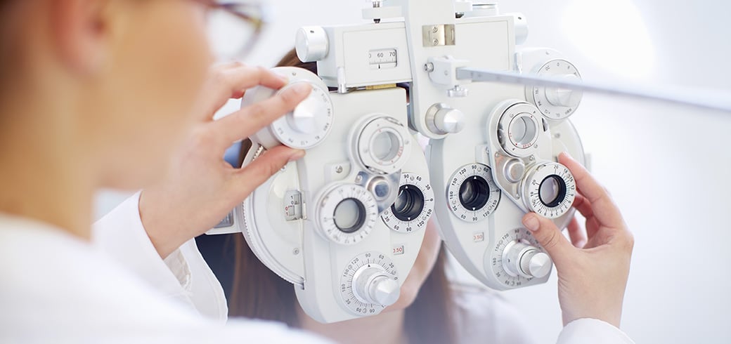 Billede af en optiker der klargøre apparat til øjenprøve.